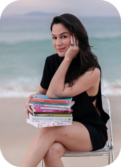 Karina Francis sentada com livros na praia