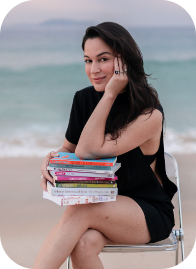 Karina Francis sentada com livros na praia