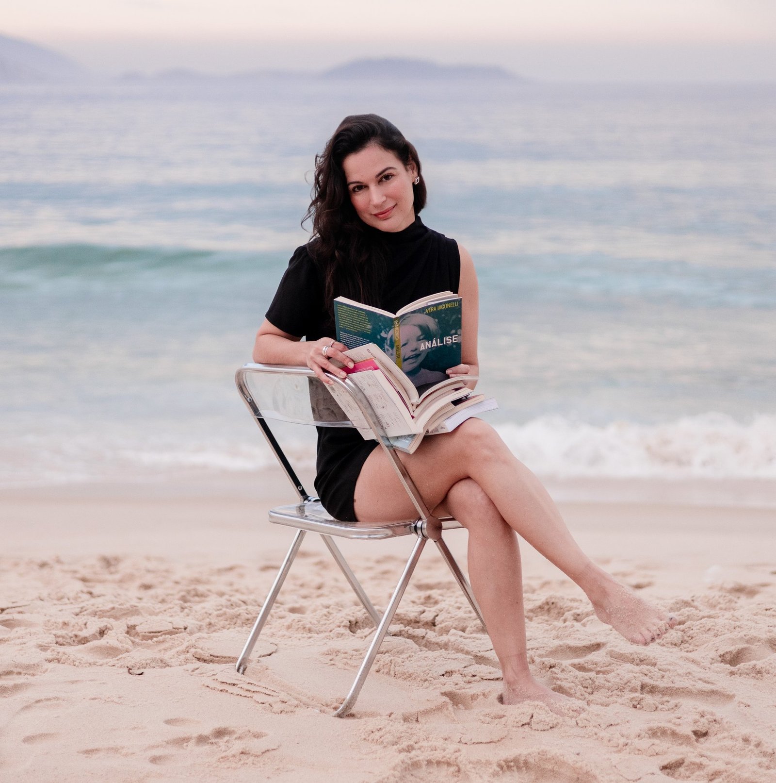 Karina Francis lendo um livro numa cadeira à beira-mar